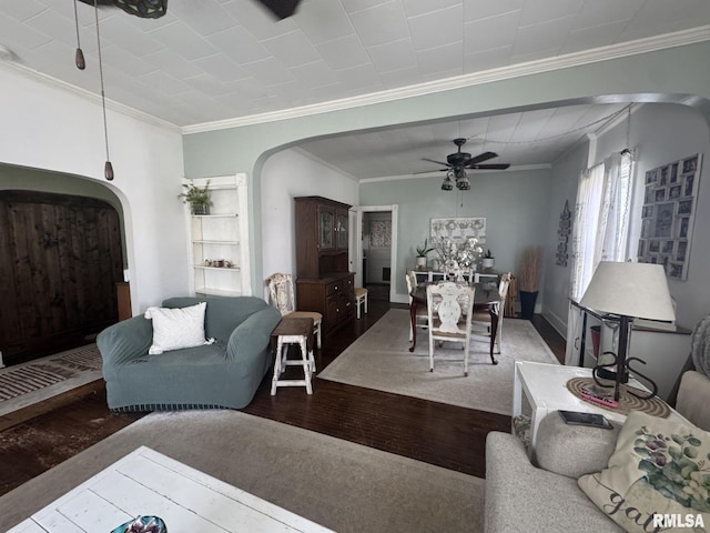 living room featuring arched walkways, ceiling fan, wood finished floors, and crown molding
