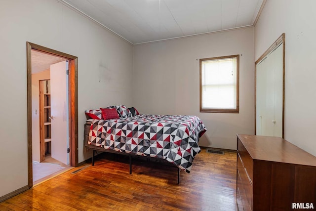 bedroom featuring visible vents, hardwood / wood-style floors, and ornamental molding