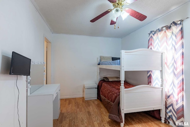 bedroom featuring multiple windows, ceiling fan, wood finished floors, and baseboards