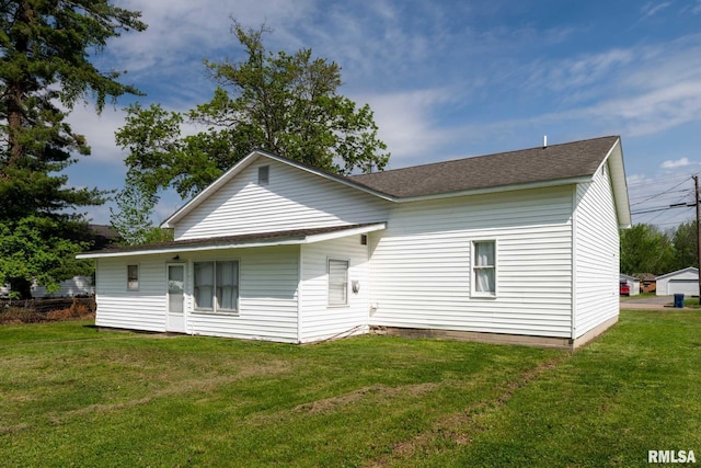 back of property featuring a lawn and roof with shingles