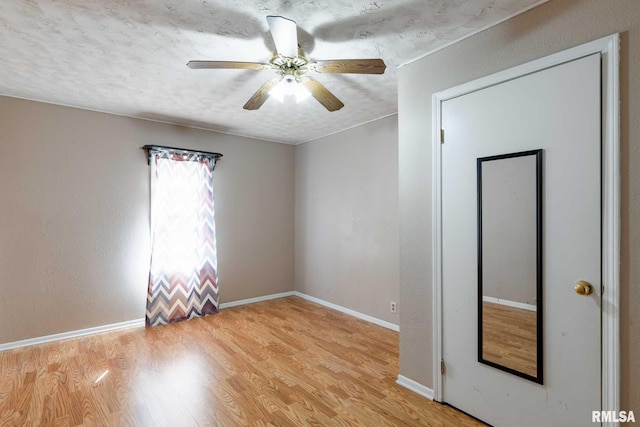 unfurnished bedroom with a textured ceiling, a ceiling fan, wood finished floors, and baseboards