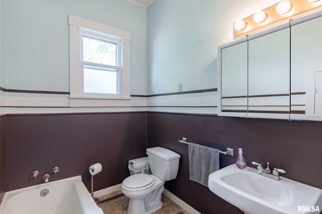 full bathroom with a sink, a bathing tub, toilet, baseboards, and tile patterned flooring