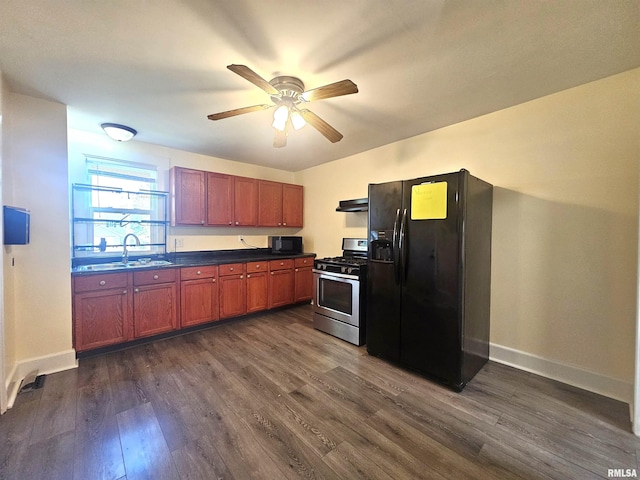 1731 W 5th St, Davenport, IA 52802 - kitchen with black appliances, under cabinet range hood, dark countertops, a ceiling fan, and dark wood-type flooring