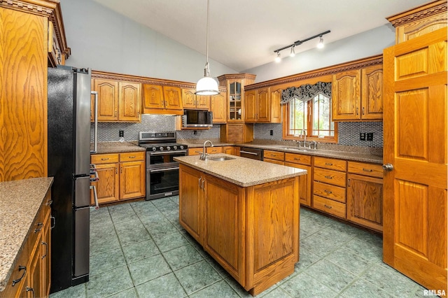kitchen with lofted ceiling, a sink, stainless steel appliances, brown cabinetry, and backsplash
