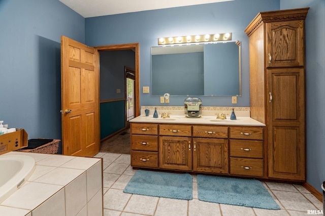 bathroom with tile patterned floors, double vanity, tiled tub, and a sink