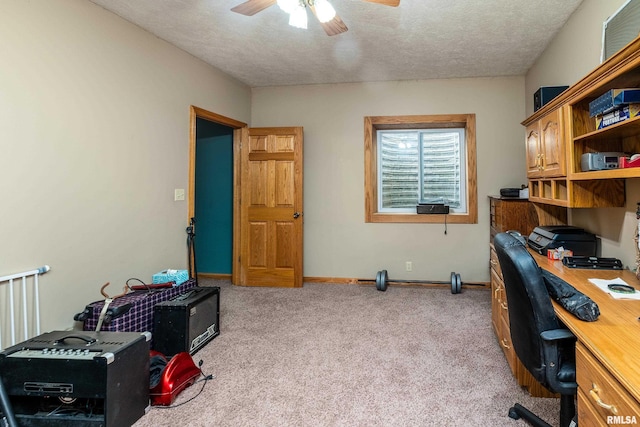 office featuring light colored carpet, a ceiling fan, baseboards, and a textured ceiling