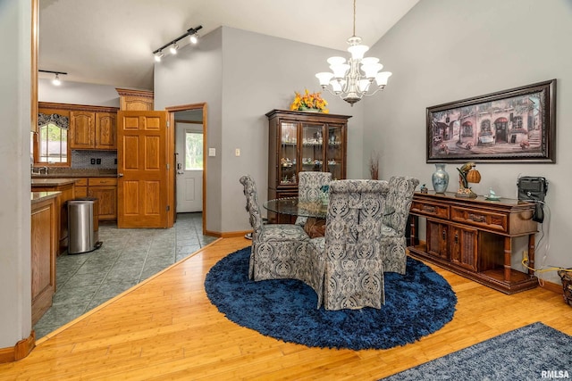 dining space with track lighting, a notable chandelier, light wood-style flooring, and baseboards