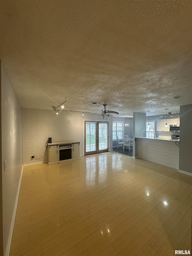 1000 N Almond St, Carbondale, IL 62901 - unfurnished living room featuring a textured ceiling, a ceiling fan, light wood-style floors, and baseboards