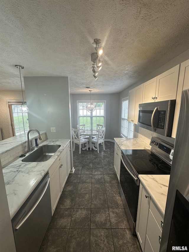 1000 N Almond St, Carbondale, IL 62901 - kitchen featuring light stone countertops, an inviting chandelier, appliances with stainless steel finishes, white cabinets, and a sink