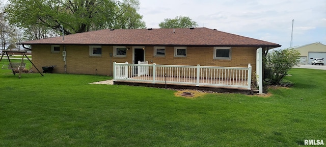back of property featuring brick siding, a deck, a yard, and roof with shingles