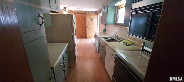 kitchen featuring stove, freestanding refrigerator, light countertops, a sink, and light wood-type flooring