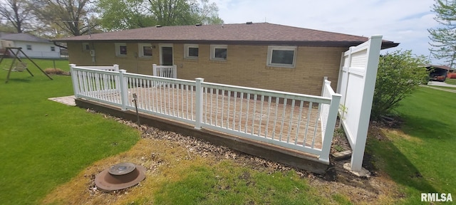 back of house with a lawn, roof with shingles, and a deck