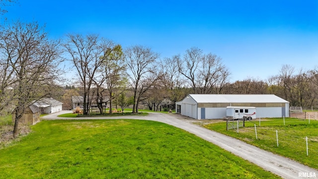 view of yard with driveway, an outdoor structure, a carport, a pole building, and fence