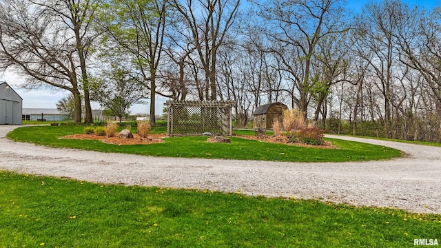 surrounding community with curved driveway, an outbuilding, and a lawn