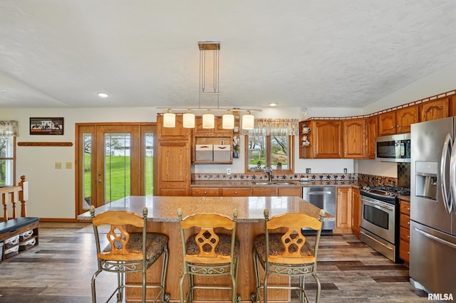 kitchen featuring dark wood finished floors, stainless steel appliances, brown cabinets, and a sink