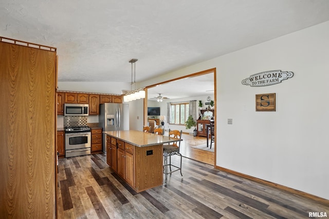 kitchen with dark wood-style flooring, brown cabinets, and stainless steel appliances