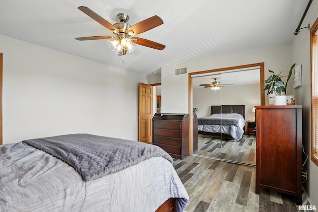 bedroom featuring wood finished floors, visible vents, a ceiling fan, and a closet