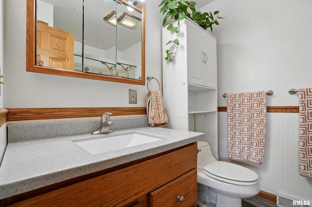 bathroom featuring visible vents, a wainscoted wall, toilet, and vanity