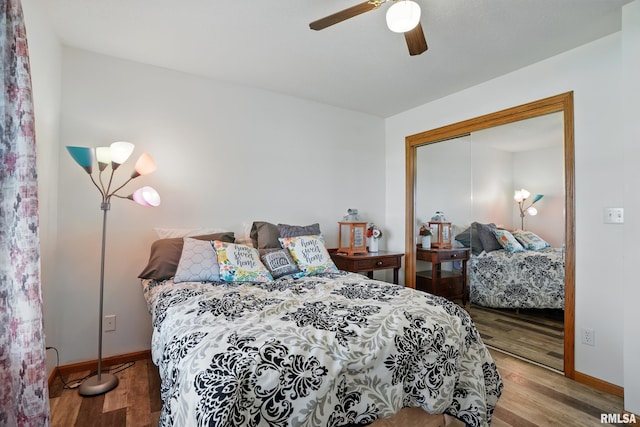 bedroom with a closet, a ceiling fan, wood finished floors, and baseboards
