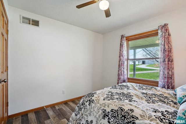 bedroom featuring wood finished floors, visible vents, a ceiling fan, and baseboards