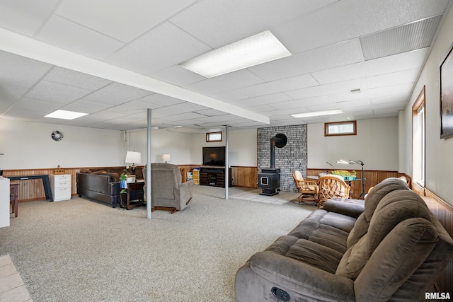 carpeted living area with a wood stove, a wainscoted wall, and wooden walls