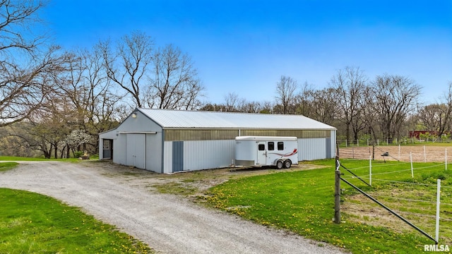 view of pole building featuring fence, driveway, and a yard