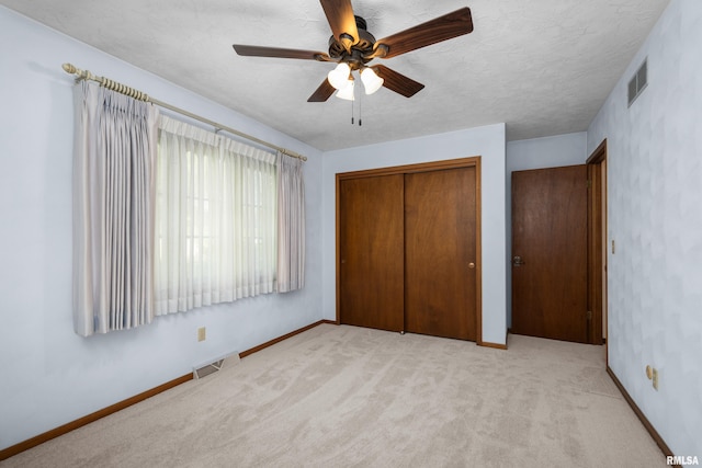 unfurnished bedroom featuring baseboards, visible vents, a closet, and light colored carpet