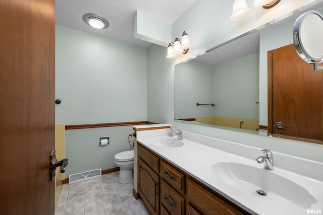 bathroom featuring double vanity, visible vents, toilet, and a sink