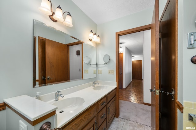bathroom featuring tile patterned floors, a textured ceiling, double vanity, and a sink