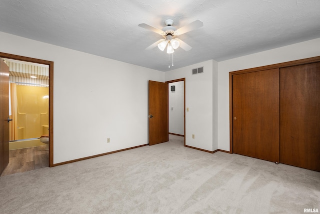 unfurnished bedroom with ensuite bath, a closet, carpet, baseboards, and visible vents