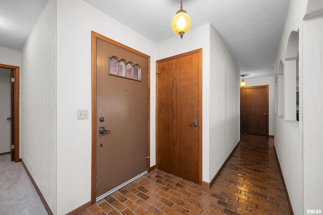 entryway featuring brick floor and baseboards