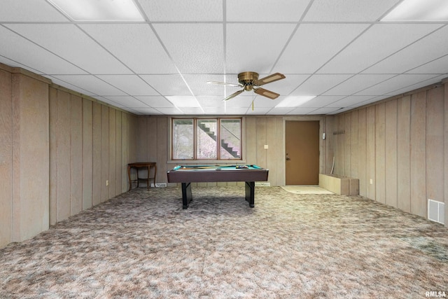 recreation room with wood walls, carpet, and a drop ceiling