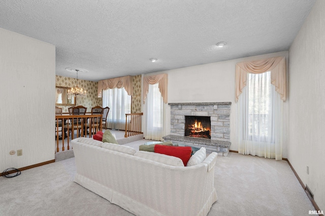 living area with a textured ceiling, a chandelier, a stone fireplace, and carpet floors