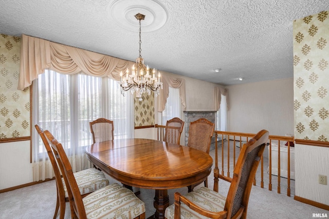 carpeted dining area featuring wallpapered walls, a notable chandelier, a textured ceiling, and plenty of natural light