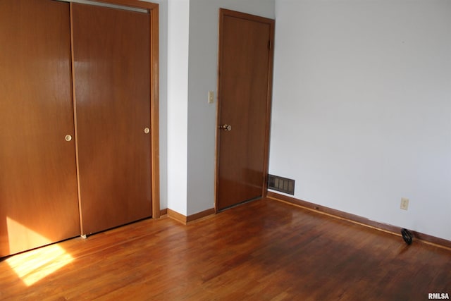 2107 W 38th Pl, Davenport, IA 52806 - unfurnished bedroom featuring baseboards, visible vents, wood finished floors, and a closet