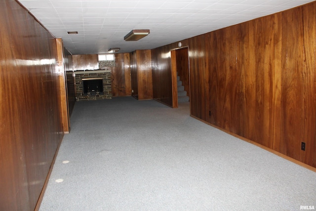 2107 W 38th Pl, Davenport, IA 52806 - below grade area with dark colored carpet, wood walls, stairs, and a fireplace