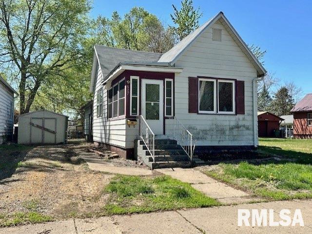 bungalow with a storage shed, entry steps, and an outbuilding