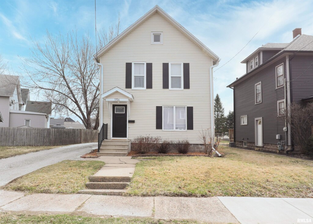 traditional-style home featuring aphalt driveway, fence, and a front yard