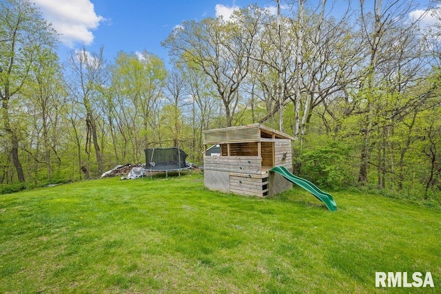 view of yard featuring a trampoline, a playground, and a forest view