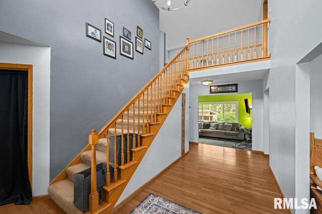 stairs with baseboards, wood finished floors, and a towering ceiling