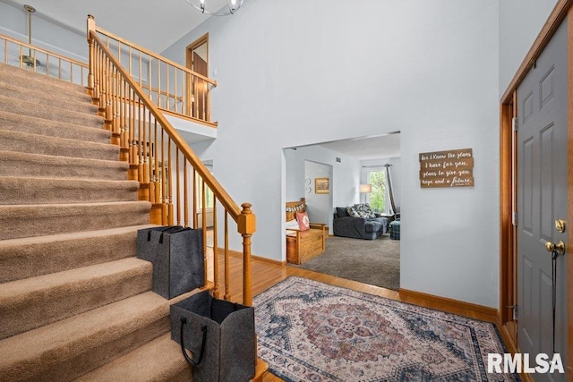 entrance foyer with baseboards, wood finished floors, stairway, and a towering ceiling
