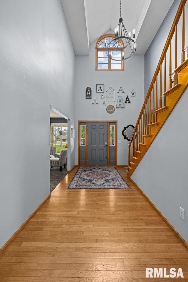 entryway with an inviting chandelier, stairs, high vaulted ceiling, and hardwood / wood-style floors