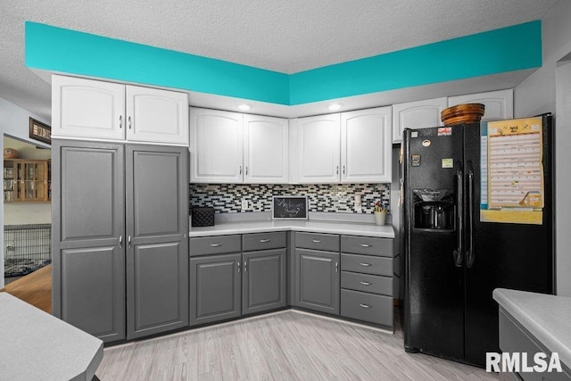 kitchen with black refrigerator with ice dispenser, light countertops, white cabinets, light wood-style flooring, and gray cabinetry