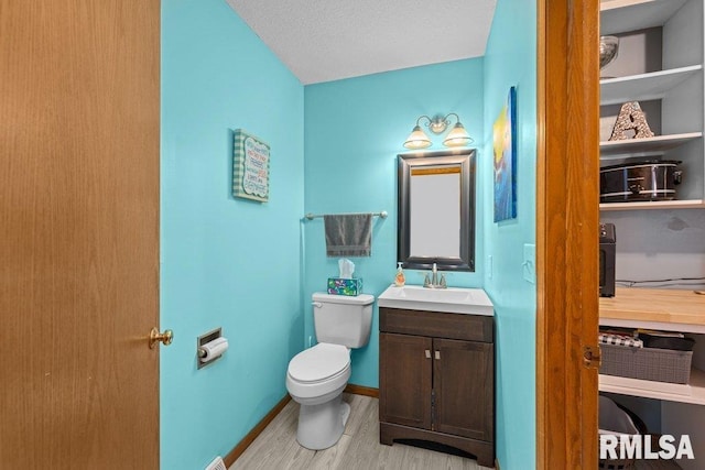 bathroom featuring vanity, baseboards, toilet, and wood finished floors