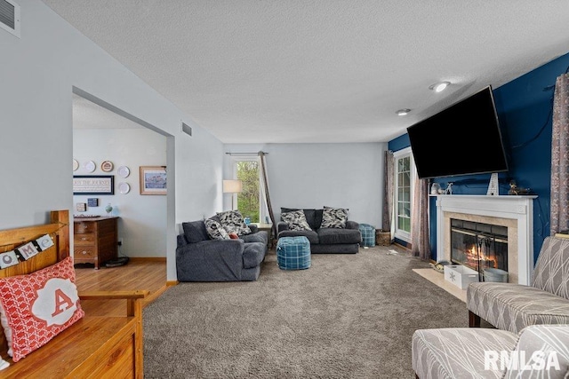 living room featuring carpet flooring, a textured ceiling, visible vents, and a fireplace