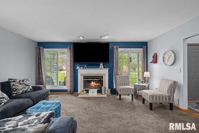 carpeted living area with a textured ceiling, plenty of natural light, and a tiled fireplace
