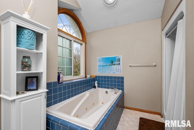 bathroom featuring a textured ceiling, a whirlpool tub, baseboards, vaulted ceiling, and visible vents