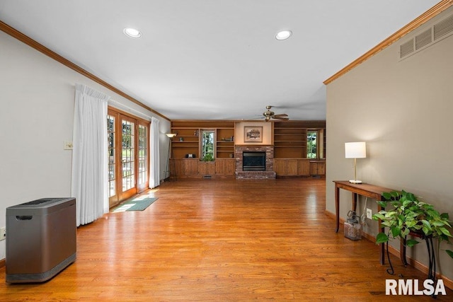 unfurnished living room with visible vents, crown molding, a ceiling fan, and a brick fireplace