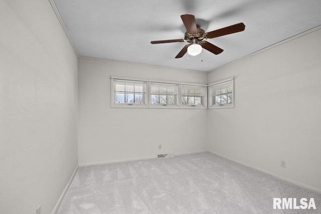 carpeted spare room featuring ceiling fan, visible vents, a healthy amount of sunlight, and baseboards