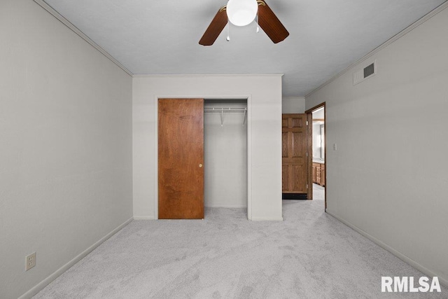 unfurnished bedroom featuring crown molding, a closet, light carpet, and baseboards